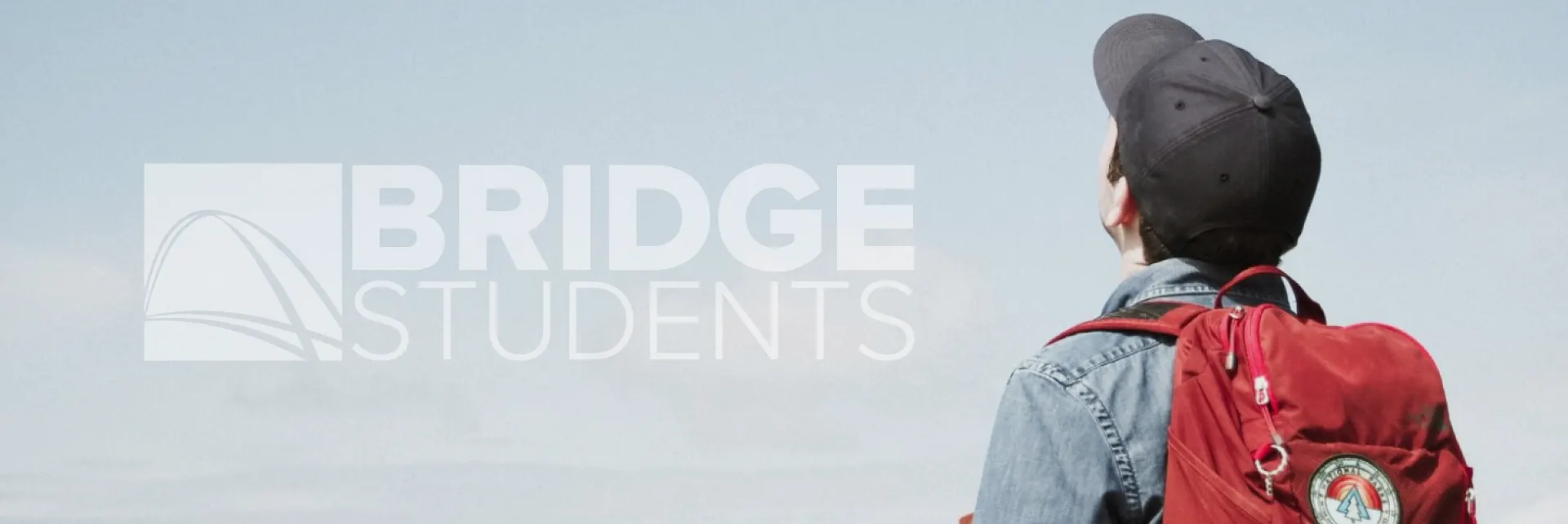 A Bridge Student wearing a backpack, looking up at the sky