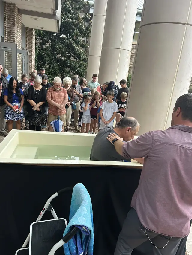 A church member being baptized while the congregation looks on